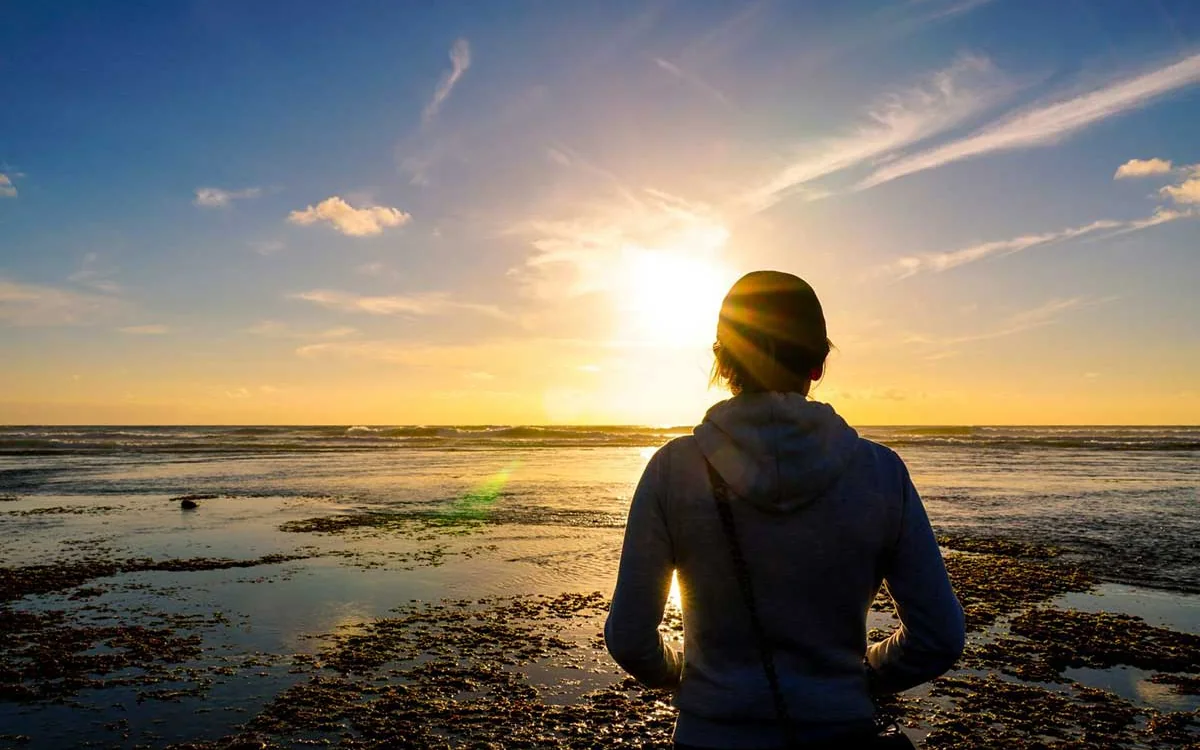 Person blickt bei Sonnenuntergang über das Wattenmeer in die Zukunft